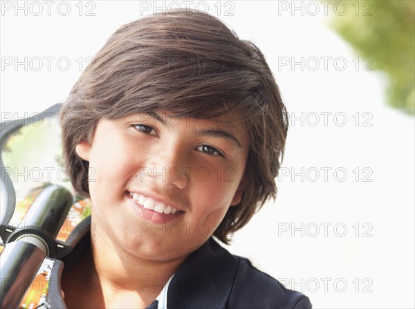 Hispanic boy carrying skateboard