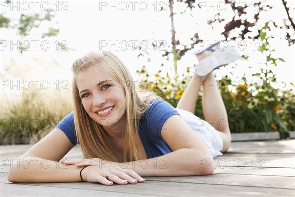 Smiling Caucasian teenager laying on deck
