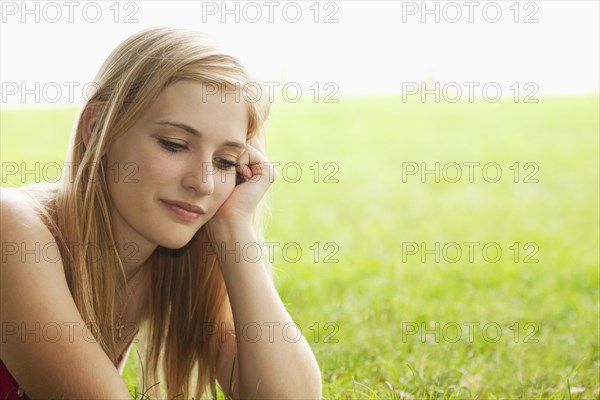 Serious Caucasian teenage girl sitting in grass