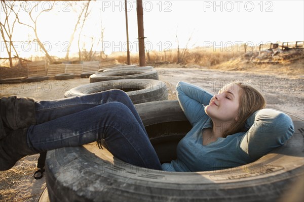 Caucasian teenager sitting in large tire