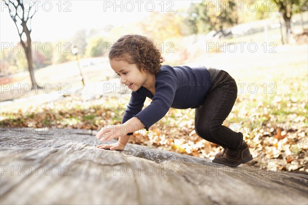 Mixed race girl climbing on rock