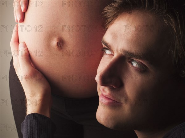 Husband listening to pregnant wife's stomach