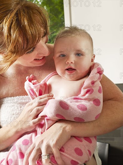 Mother wrapping baby girl in towel