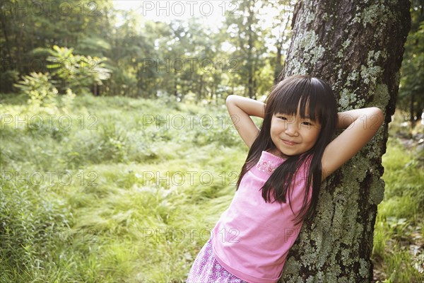 Girl leaning against tree outdoors