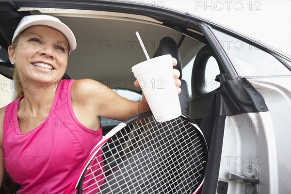 Caucasian tennis player climbing out of car