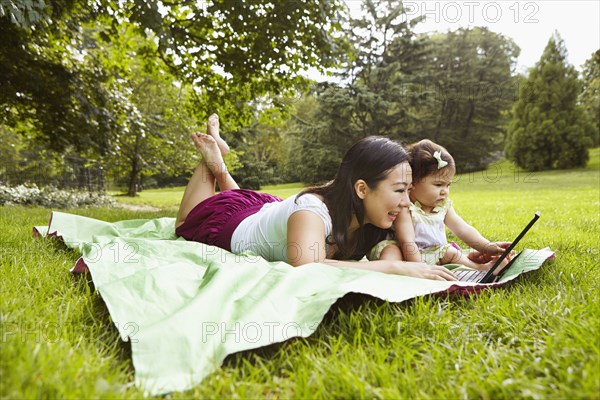 Mother and baby girl using laptop in park