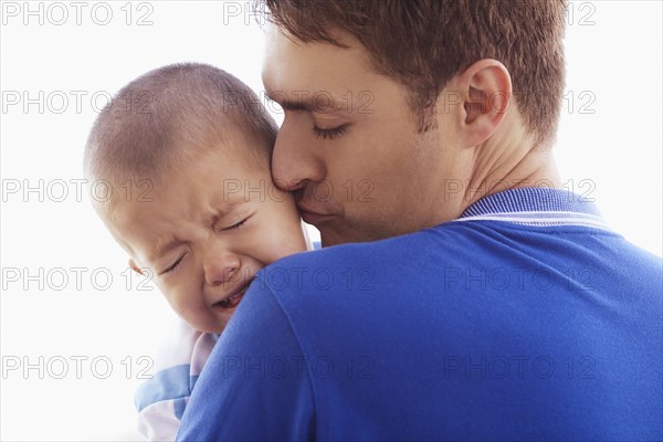 Father kissing crying son