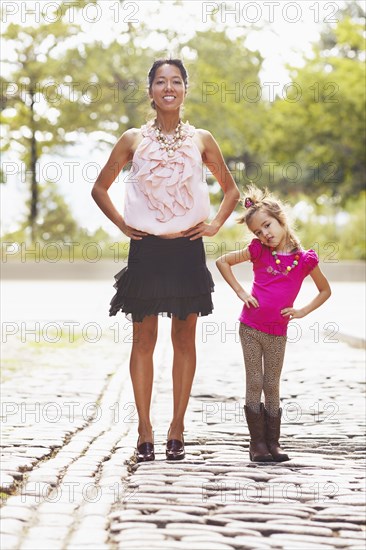 Mother and daughter posing on city street