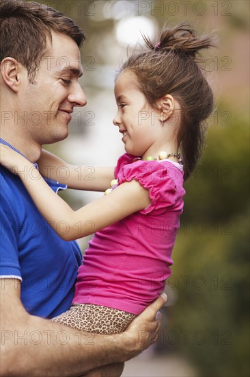 Father holding daughter on city street