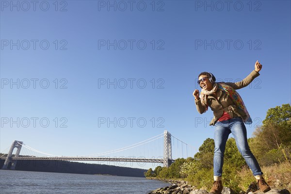 Black woman listening to headphones at river