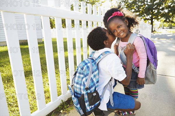 Mixed race boy whispering in sister's ear