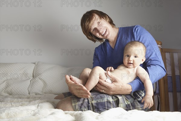 Father holding baby on bed