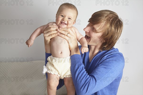 Father holding baby on bed