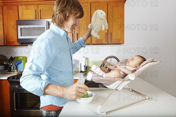 Father playing with baby in chair