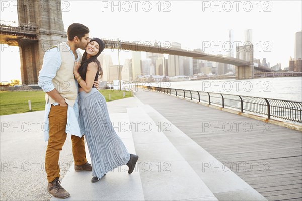 Indian couple kissing by bridge