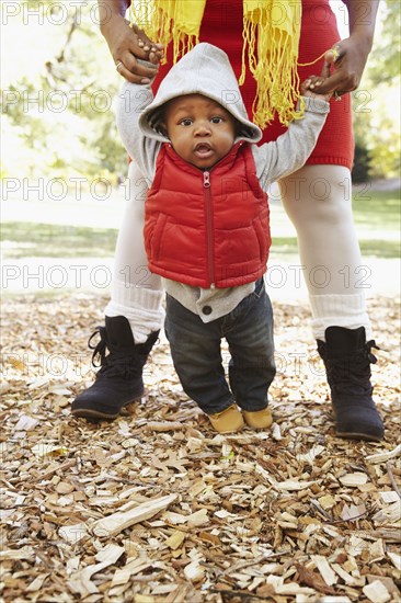 Black mother and toddler son playing in park