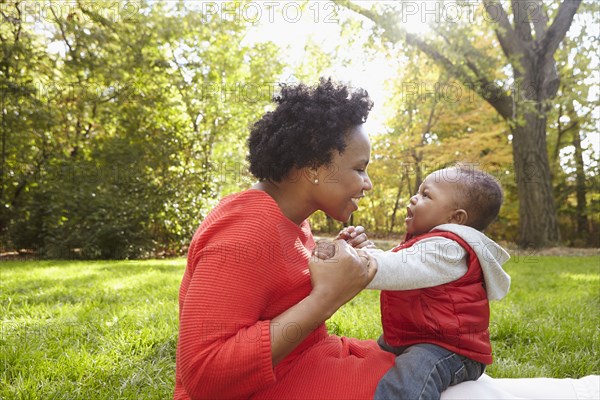 Black mother and toddler son playing in park