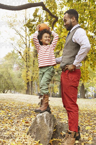 Father and son holding pumpkin in park