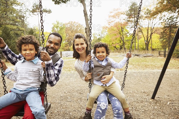 Family sitting on swings in park