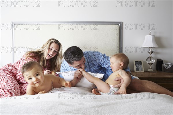 Caucasian family playing on bed