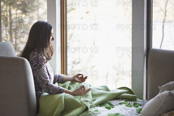 Caucasian woman meditating on sofa