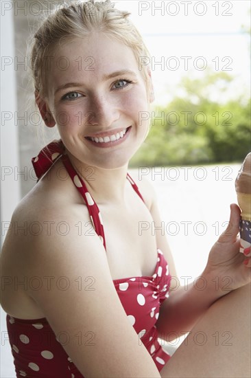 Smiling woman in swimsuit eating ice cream cone