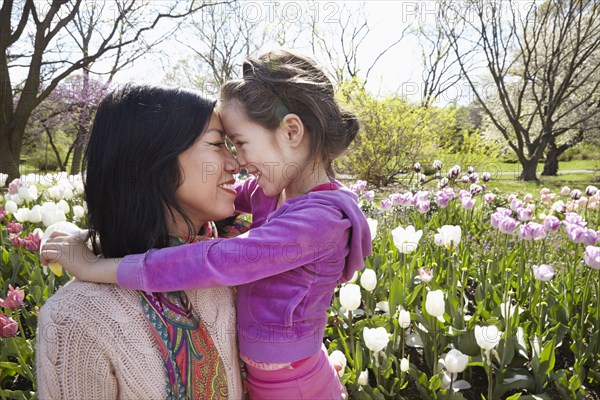 Mother and daughter rubbing noses in park