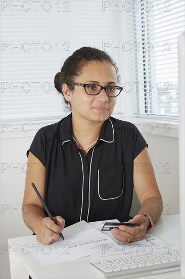 Hispanic businesswoman shopping online at desk