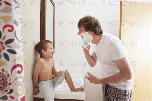 Father teaching son to shave in bathroom