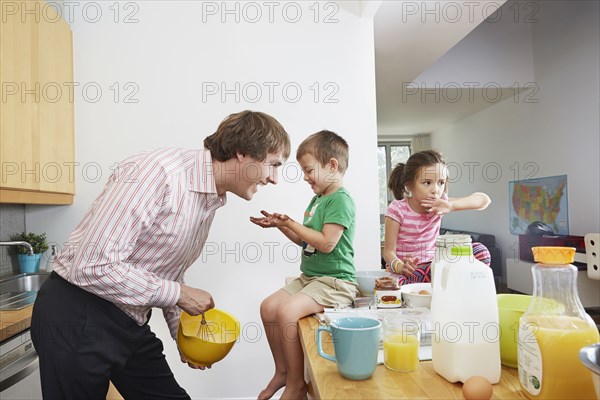 Father making breakfast for children in kitchen