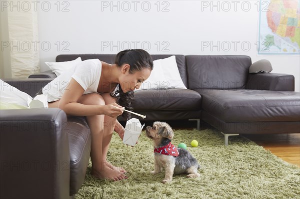 Chinese woman feeding dog takeout in living room