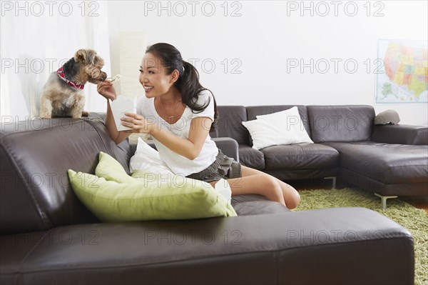 Chinese woman feeding dog takeout in living room