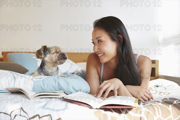 Chinese woman relaxing with dog on bed