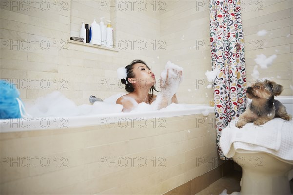 Chinese woman playing in bubble bath with dog