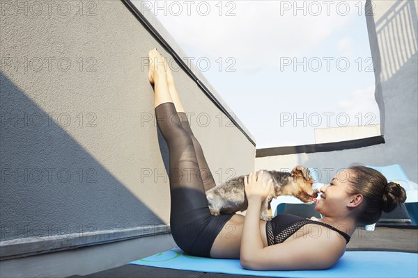Chinese woman practicing yoga with dog on deck