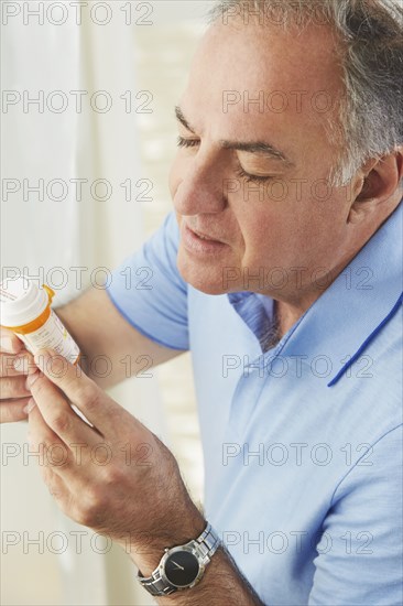 Hispanic man reading prescription medication bottle