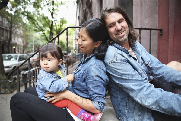 Family sitting on front stoop in city