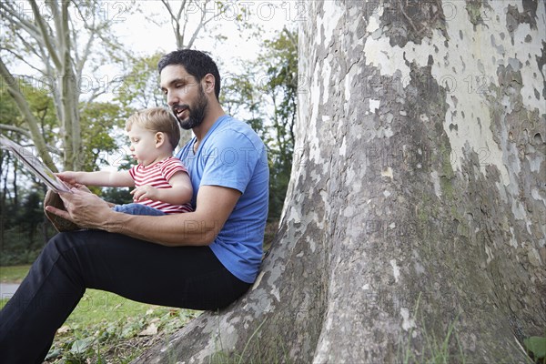 Caucasian father and baby son using digital tablet outdoors