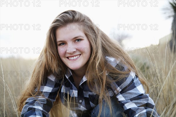 Smiling woman sitting in tall grass