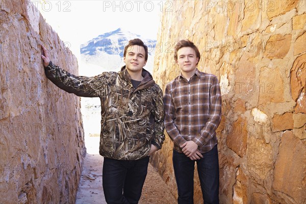 Smiling men standing between rock walls