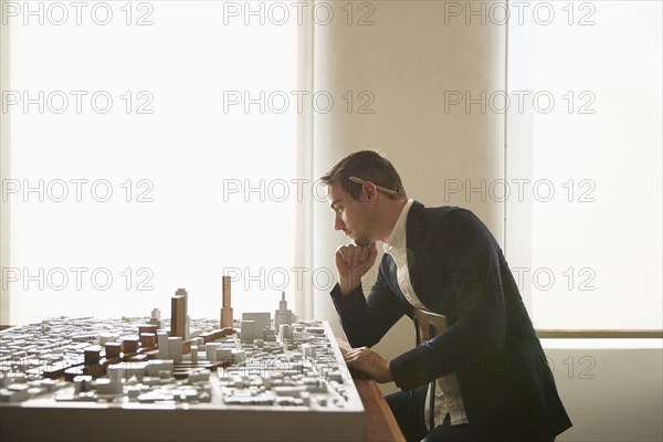 Caucasian architect examining urban model in office