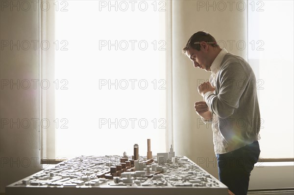 Caucasian architect examining urban model in office