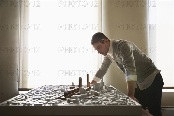 Caucasian architect examining urban model in office