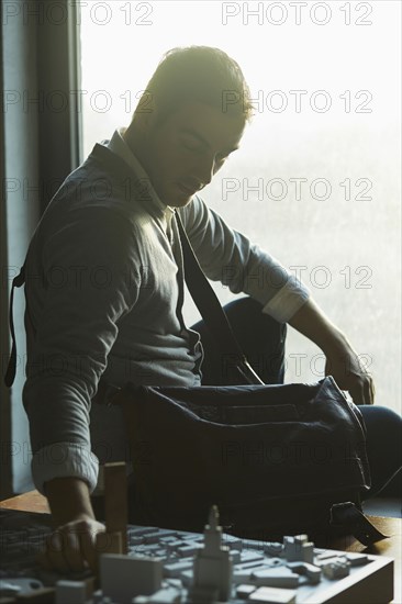 Caucasian architect at office window examining urban model