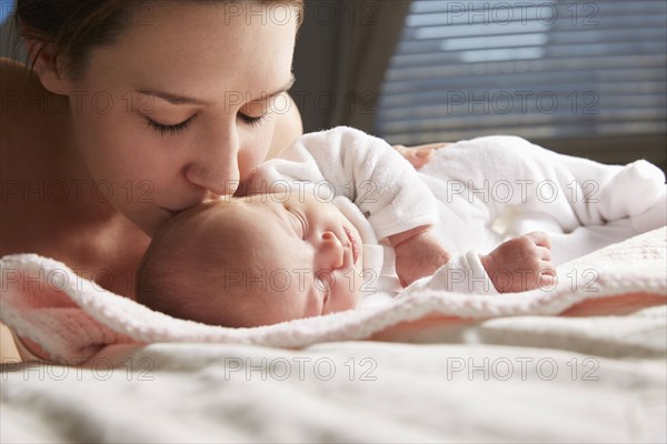 Mother kissing newborn baby on blanket