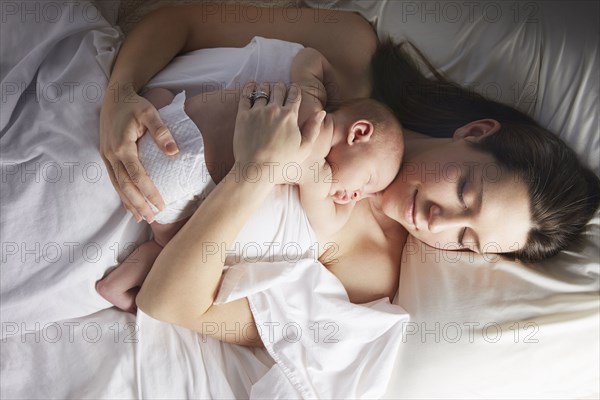 Mother sleeping with newborn baby on bed