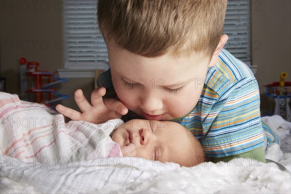 Boy admiring newborn sibling on bed