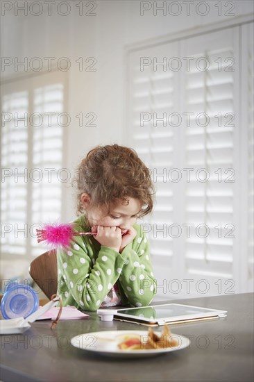 Caucasian girl using digital tablet at table