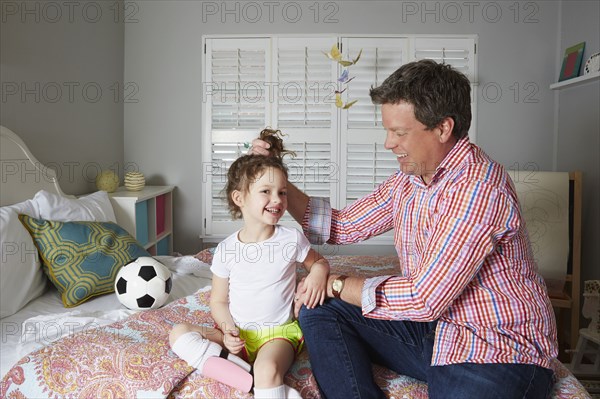 Caucasian father holding hair of daughter