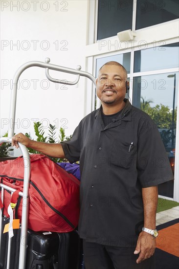 Hispanic bellboy holding luggage at hotel